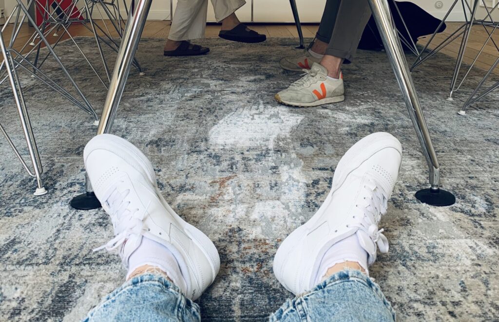 Unterschiedliche Schuhe unter einem Tisch als Symbolbild für Diversity in der Agenturbranche
